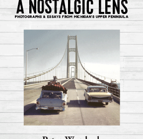 Cover of the book "A Nostalgic Lens: Photographs & Essays from Michigan's Upper Peninsula" by Peter Wurdock. It features two vintage cars crossing a large suspension bridge, likely the Mackinac Bridge. The background has a wooden plank texture.