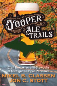 Book cover for "yooper ale trails" featuring an illustration of a pint of beer with an outline of michigan's upper peninsula in green. vibrant autumn trees in the background, with author names mikel b. classen and jon c. stott.