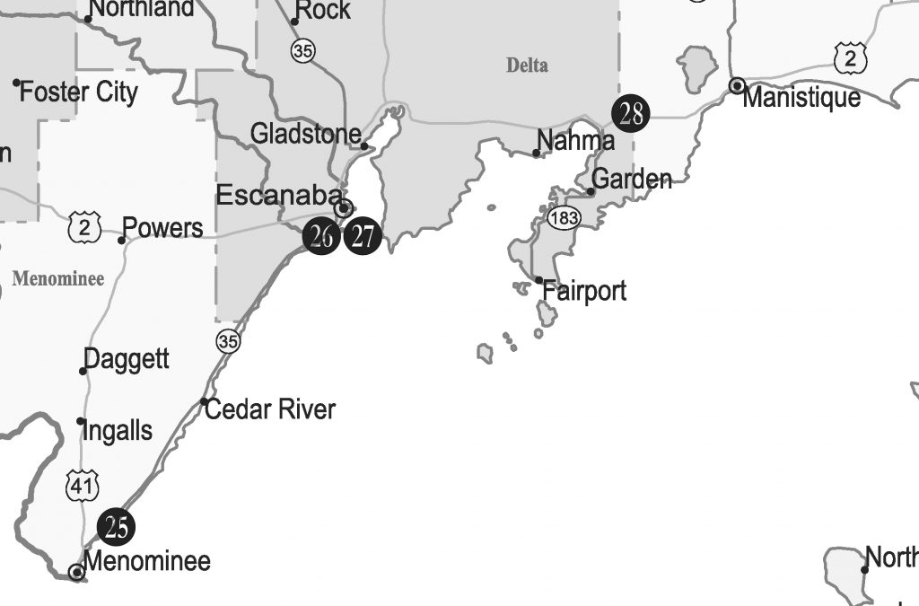 A grayscale map showing a section of Michigan's Upper Peninsula along the Lake Michigan coastline. Towns marked include Menominee (with number 25), Cedar River, Escanaba (26, 27), Gladstone, Nahma (28), Garden, Fairport, and Manistique.